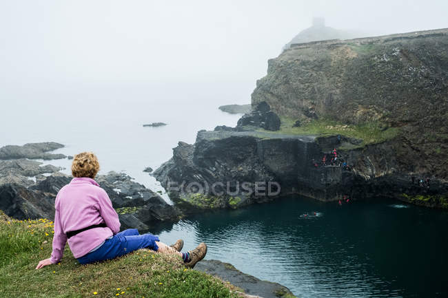 Frau sitzt auf Klippe an der Küste von Pembrokeshire, Wales, Großbritannien. — Stockfoto
