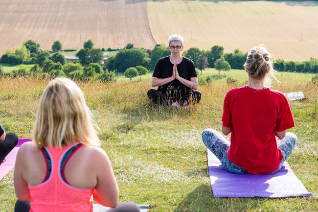 Group of women taking part in outdoor yoga class on a hillside. — Stock Photo