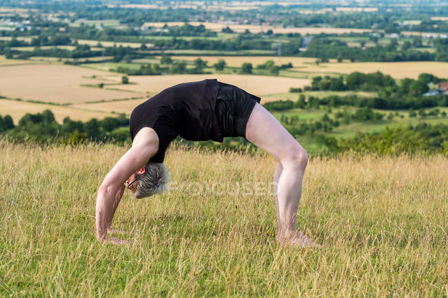 Femme mûre prenant part à un cours de yoga en plein air sur une colline . — Photo de stock
