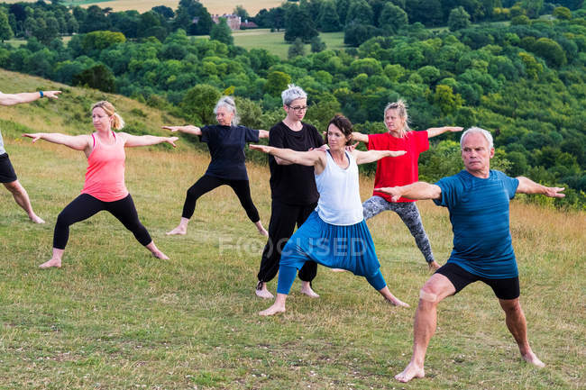 Gruppe von Frauen und Männern nimmt an einem Yoga-Kurs im Freien am Hang teil. — Stockfoto