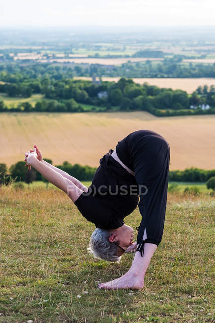 Reife Frau nimmt an Outdoor-Yoga-Kurs an einem Hang teil. — Stockfoto