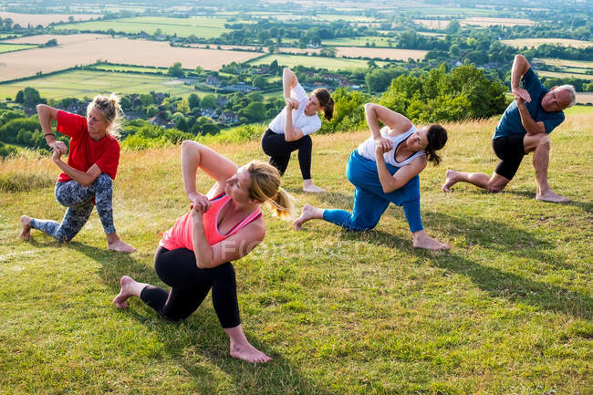 Група жінок і чоловіків, які беруть участь у відкритому класі йоги на схилі пагорба.. — стокове фото