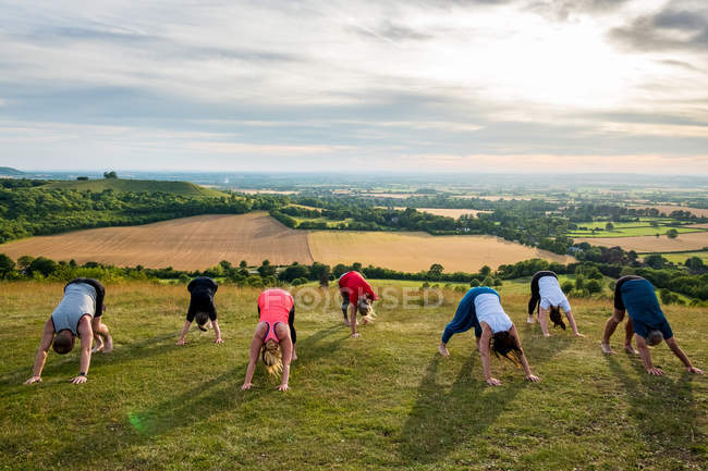 Група жінок і чоловіків беруть участь у класі йоги на схилі пагорба . — стокове фото