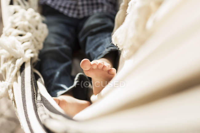 Ноги хлопчика початкового віку лежать в гамаку на ганку — стокове фото