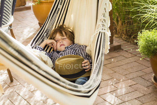 Bonito elementar idade menino dormindo no rede no alpendre — Fotografia de Stock