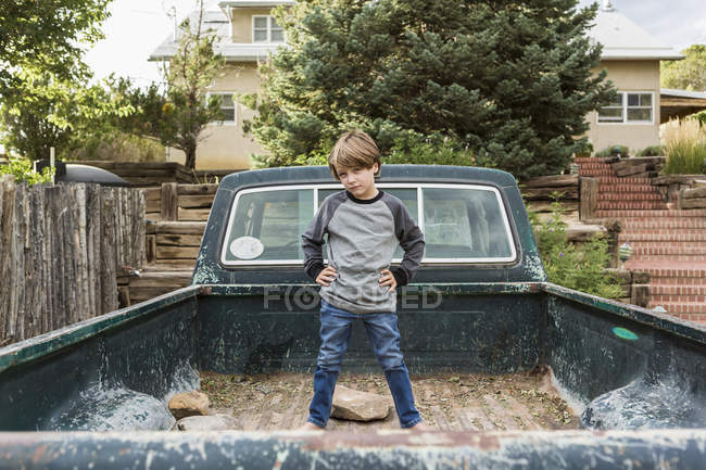Porträt eines Jungen im Grundschulalter, der im Bett eines alten Pick-ups posiert — Stockfoto