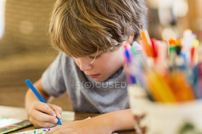 Elementary age boy drawing with colorful pens — Stock Photo