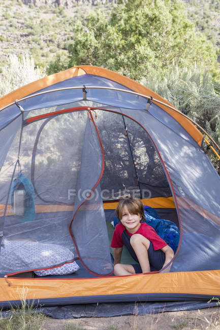 Retrato de menino de idade elementar sentado na tenda — Fotografia de Stock