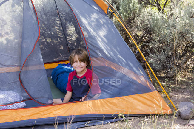 Portrait of pre-teen boy sitting in tent in nature — Stock Photo