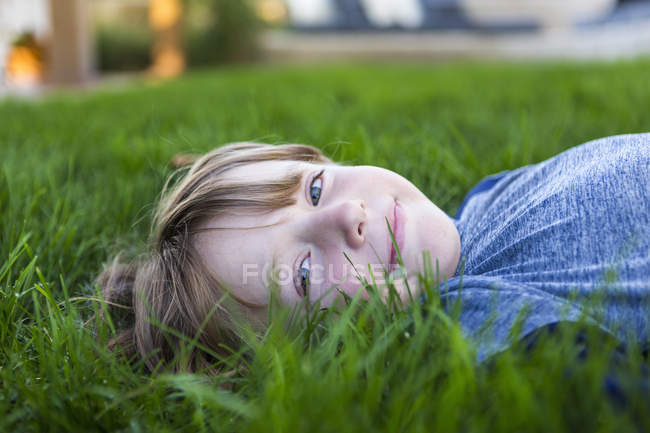 Портрет усміхненого хлопчика, який лежить у зеленій траві — стокове фото