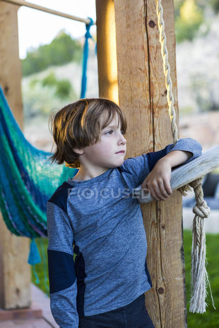 Retrato del niño preadolescente apoyado en el columpio en el jardín - foto de stock