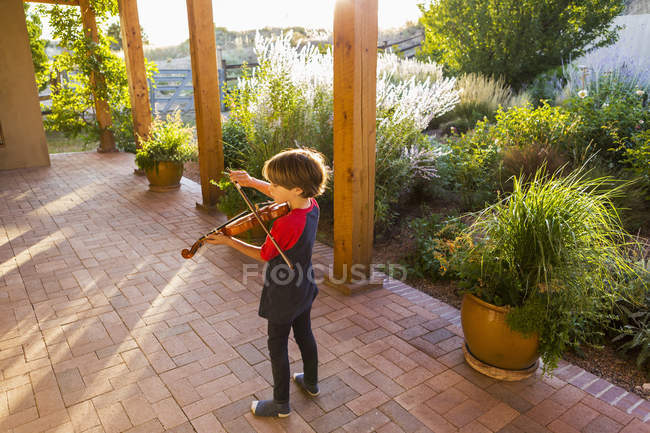 Petit garçon jouant du violon dehors dans le jardin — Photo de stock