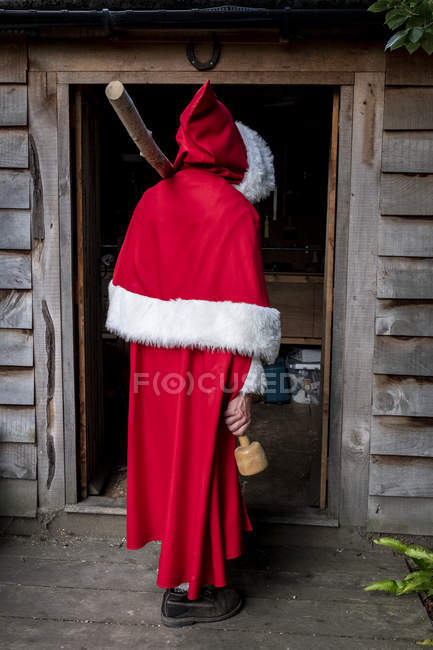 Rückansicht eines Mannes im Weihnachtsmann-Kostüm, der in der Werkstatttür steht. — Stockfoto
