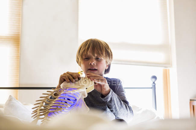 Little boy playing with fish toy on bed — Stock Photo