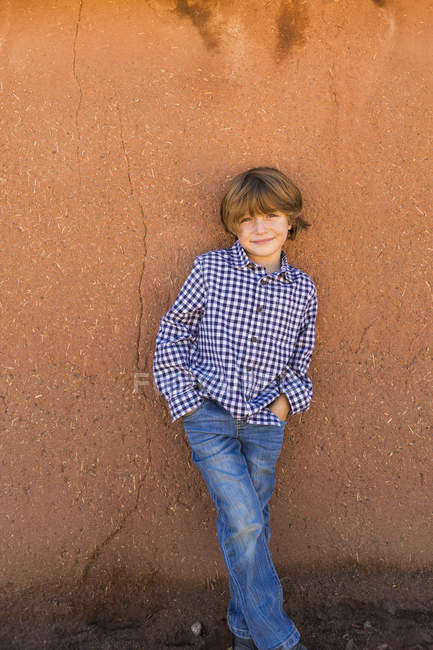Портрет хлопчика початкового віку проти стіни адобе — стокове фото