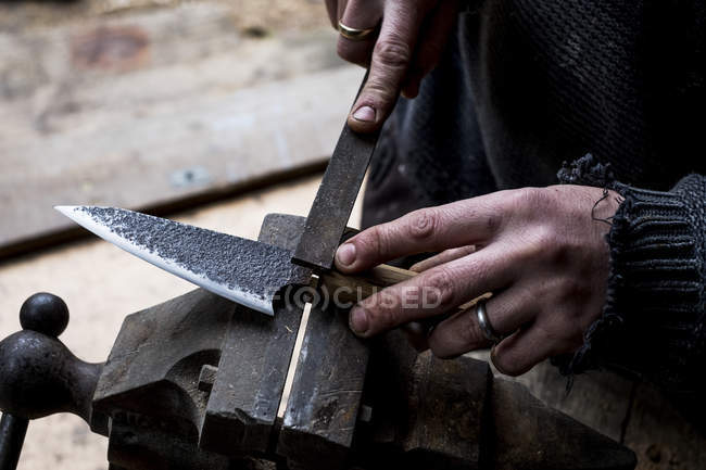 Plan rapproché grand angle de la personne travaillant sur un couteau fait à la main à l'aide d'un fichier . — Photo de stock