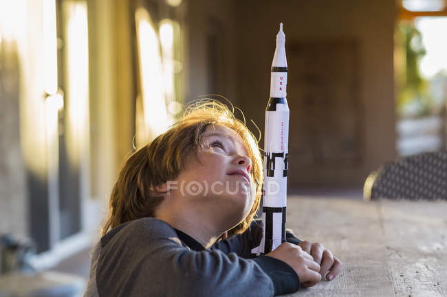 Elementary age boy playing with toy rocket, daydreaming about space flight. — Stock Photo