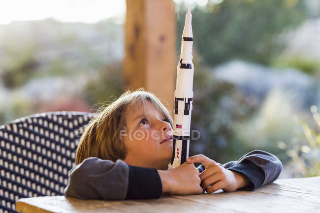 Elementary age boy playing with toy rocket, daydreaming about space flight. — Stock Photo