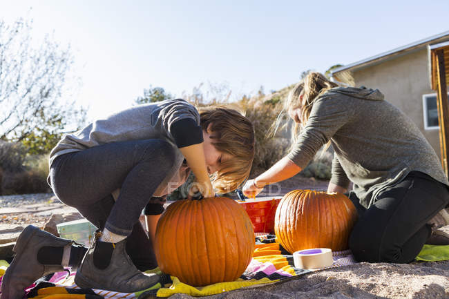 Adolescente y niño de edad elemental tallando calabazas en Halloween . - foto de stock