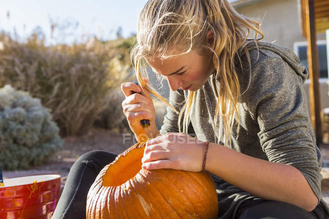 Chica adolescente tallando calabaza grande en Halloween . - foto de stock