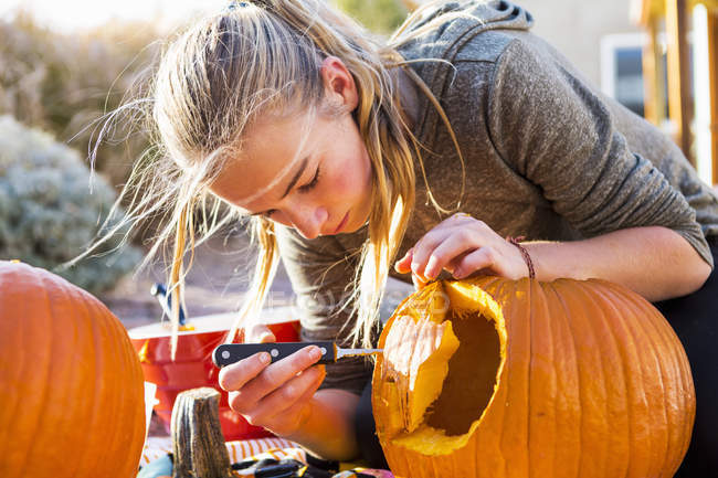 Adolescente esculpindo grande abóbora no Halloween . — Fotografia de Stock
