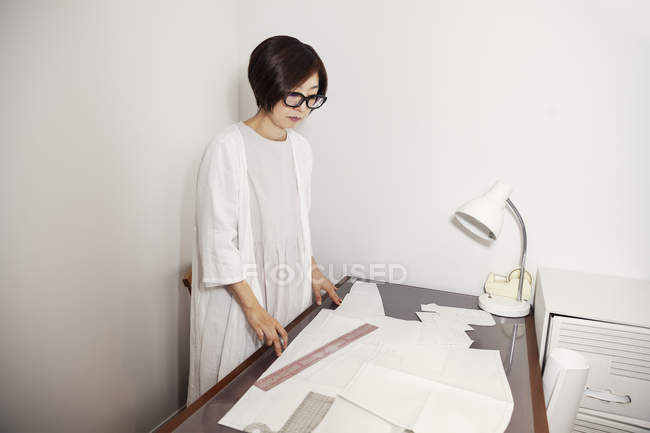 Mulher japonesa em óculos trabalhando em uma mesa em uma pequena boutique de moda . — Fotografia de Stock