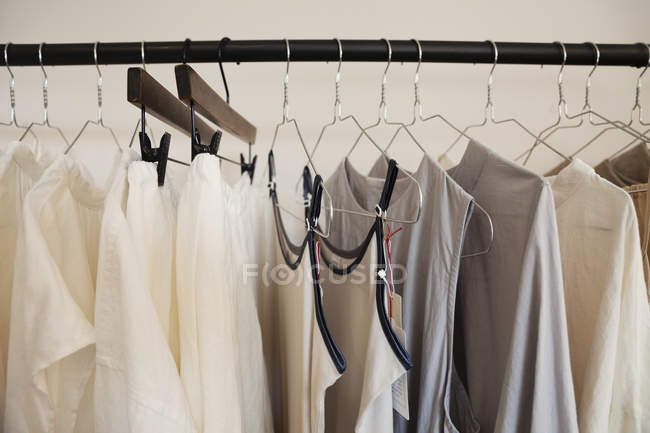 Primo piano di selezione di vestiti in colori naturali su una rotaia in una boutique . — Foto stock