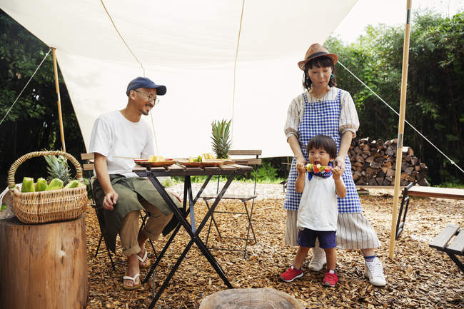Japaner, Frau und Junge versammelten sich um einen Tisch unter einem Baldachin und bereiteten Gemüse zu. — Stockfoto