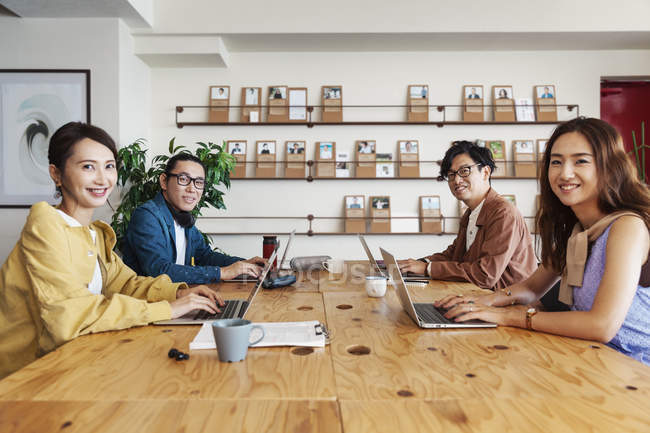 Группа японских коллег, работающих на ноутбуках в коворкинг-пространстве . — стоковое фото