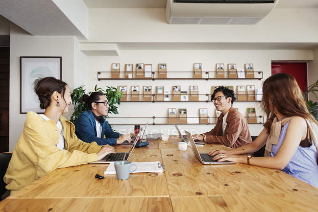 Gruppo di imprenditori giapponesi che lavorano su computer portatili in uno spazio di co-working . — Foto stock