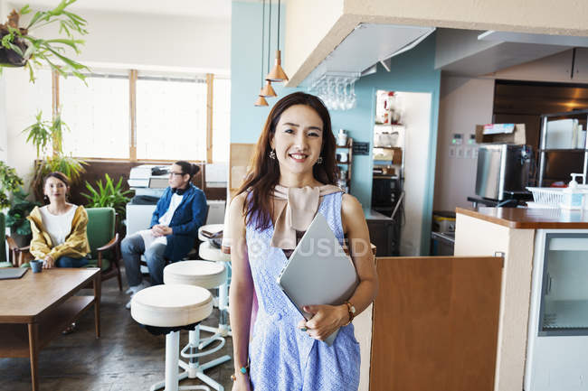 Female Japanese professional standing in a co-working space, smiling in camera. — Stock Photo