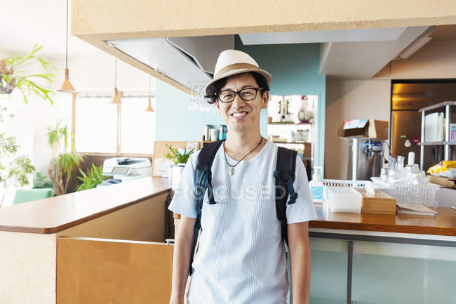 Maschio giapponese professionale in piedi in un co-working spazio, sorridente in macchina fotografica . — Foto stock