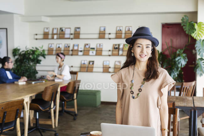 Woman standing in front of Japanese professionals working on laptop computer in a co-working space. — Stock Photo