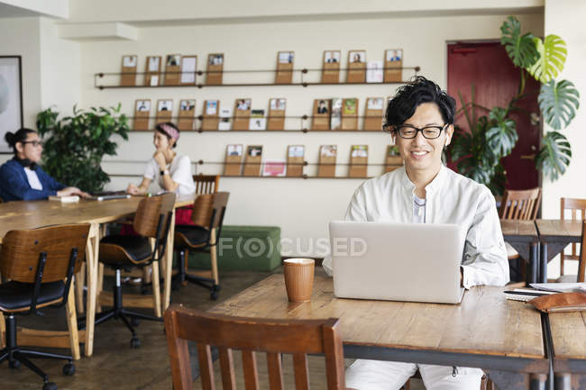 Des hommes d'affaires japonais travaillant sur un ordinateur portable dans un espace de co-travail . — Photo de stock