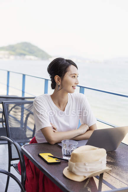 Empresária japonesa sentada na varanda de um espaço de co-trabalho, usando computador portátil . — Fotografia de Stock