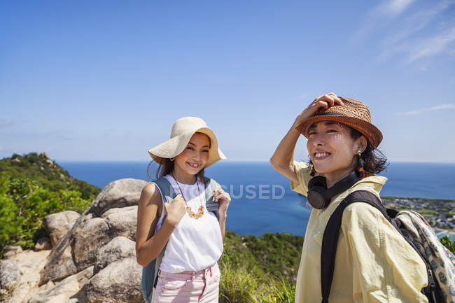 Zwei japanische Frauen mit Hüten stehen auf einer Klippe mit Meereslandschaft. — Stockfoto