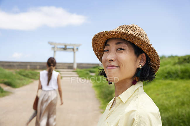 Dos mujeres japonesas de pie en un camino junto al santuario sintoísta . - foto de stock