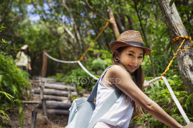 Japanese woman wearing hat hiking in a forest. — Stock Photo