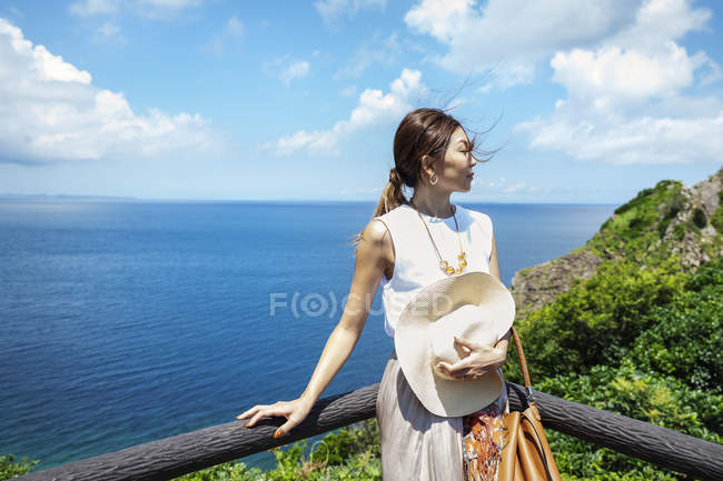 Japanese woman standing on a cliff with ocean scenery. — Stock Photo