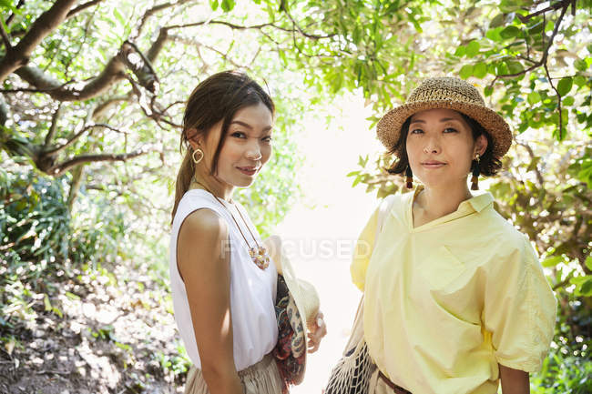 Zwei japanische Frauen mit Hüten wandern in einem Wald. — Stockfoto