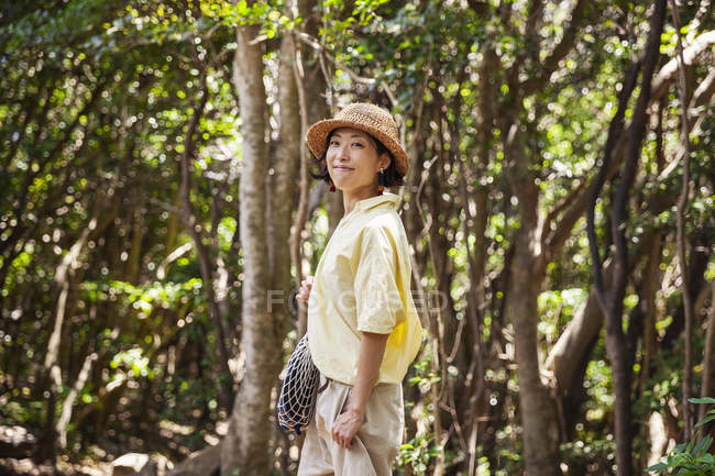 Japanerin mit Hut wandert im Wald. — Stockfoto