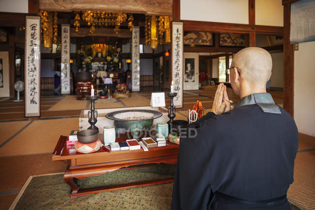 Prêtre bouddhiste agenouillé dans le temple bouddhiste, priant . — Photo de stock