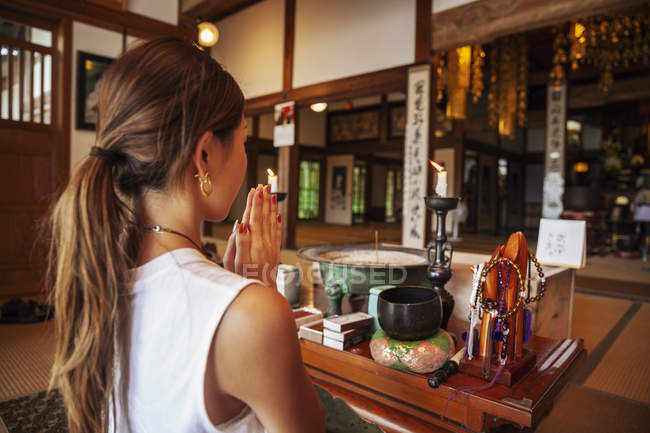 Японка стоїть навколішки у буддійському храмі і молиться.. — стокове фото