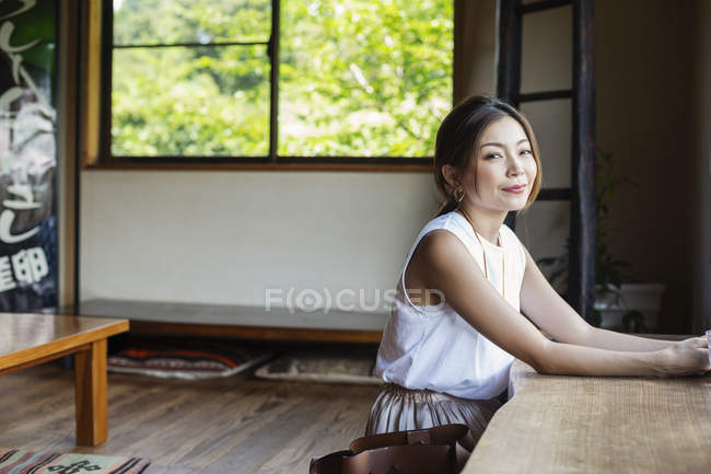 Lächelnde Japanerin sitzt an einem Tisch in einem japanischen Restaurant. — Stockfoto