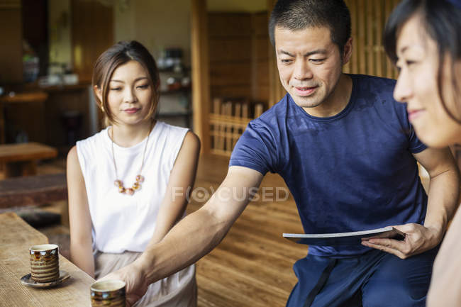 Официант обслуживает двух японских женщин, сидящих за столом в японском ресторане . — стоковое фото