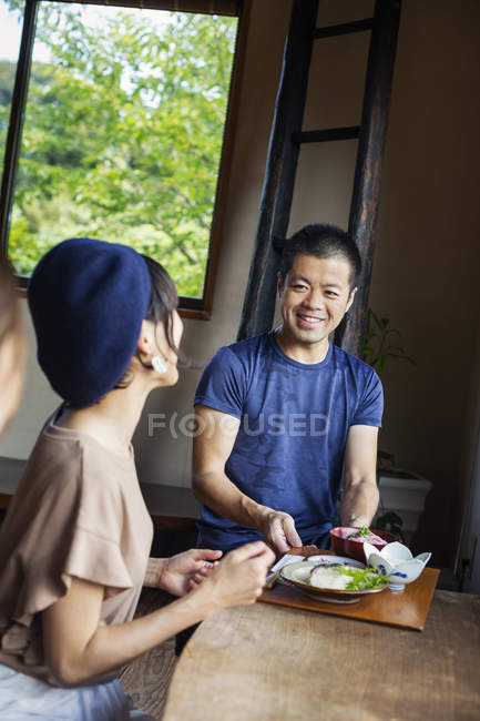 Camarero sirviendo mujeres sentadas en una mesa en un restaurante japonés . - foto de stock