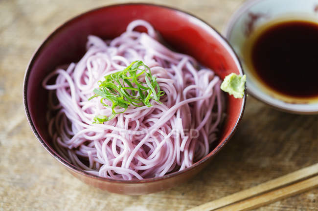 Alto ángulo de primer plano de tazón de fideos rosados en una mesa en el restaurante japonés . - foto de stock