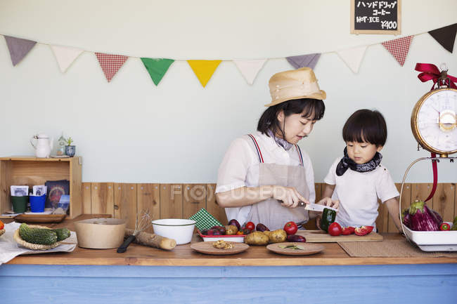Japonês mulher e menino de pé em uma loja de fazenda, preparando comida . — Fotografia de Stock