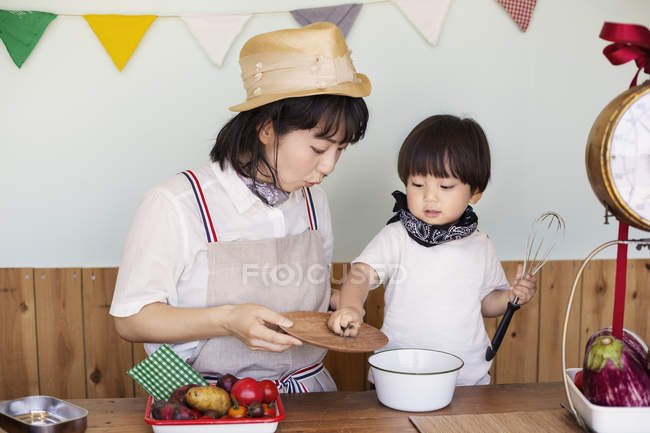 Japonês mulher e menino de pé em uma loja de fazenda, preparando comida . — Fotografia de Stock