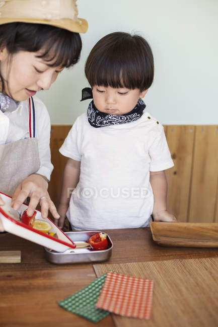 Japanerin und Junge stehen in einem Hofladen und bereiten Essen zu. — Stockfoto